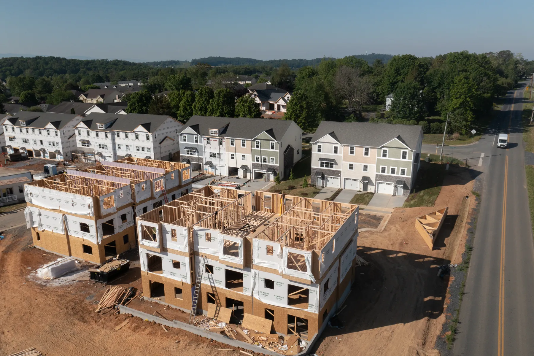 Aerial view of townhouses under construction beside finished units in a new development